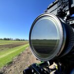 Close-up of a camera lens capturing outdoor video content in a scenic landscape